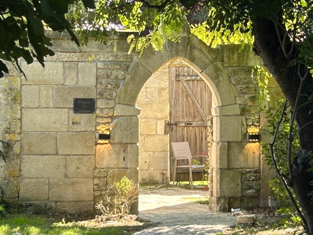 une arche dans un bâtiment en pierre avec une porte en bois dans l'établissement Demeures et Châteaux - Le Portail en Marais Poitevin, à Moreilles