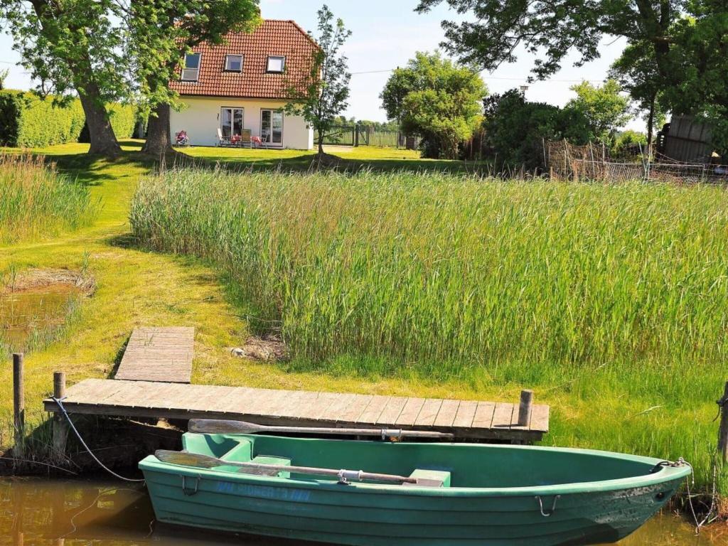 a green boat on the water next to a dock at Holiday home Crane Coast in Kinnbackenhagen