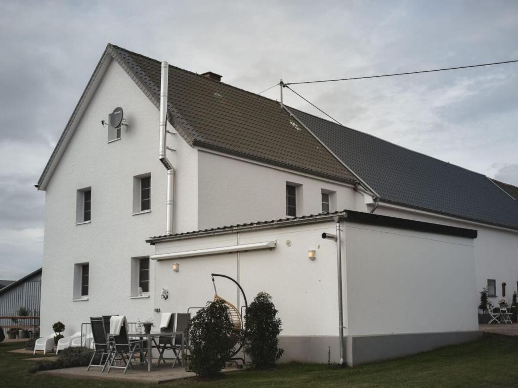 a white house with a table and chairs in front of it at Country love -Holiday on the horse farm- in Frauenkron