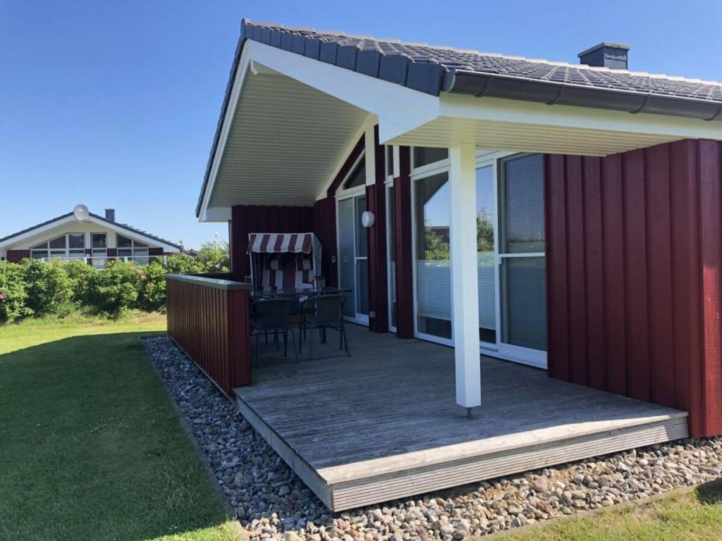 Huus Naturstrand am Diek في Wesselburen: منزل احمر مع سطح مع طاولة