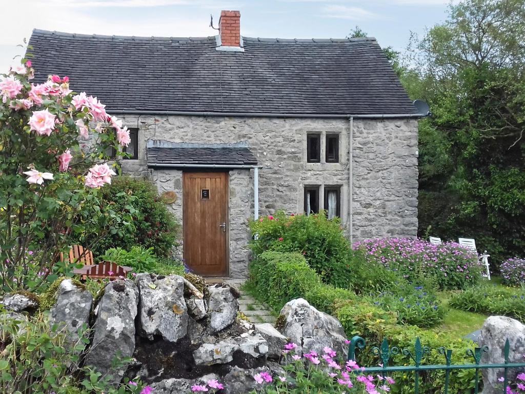 a stone house with a wooden door in a garden at Ivy Cottage in Elton