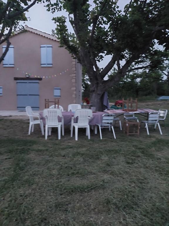 un groupe de chaises et de tables blanches sous un arbre dans l'établissement Bastidon, à La Celle-sous-Gouzon