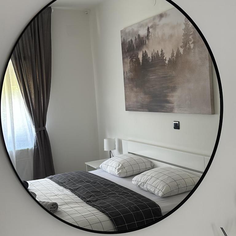 a mirror reflecting a bedroom with a bed and a picture at Cor Montis Apartments in Krasno Polje