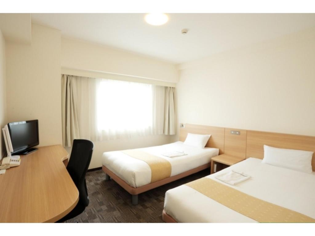 a hotel room with two beds and a desk at Smile Hotel Kumagaya - Vacation STAY 64094v in Kumagaya