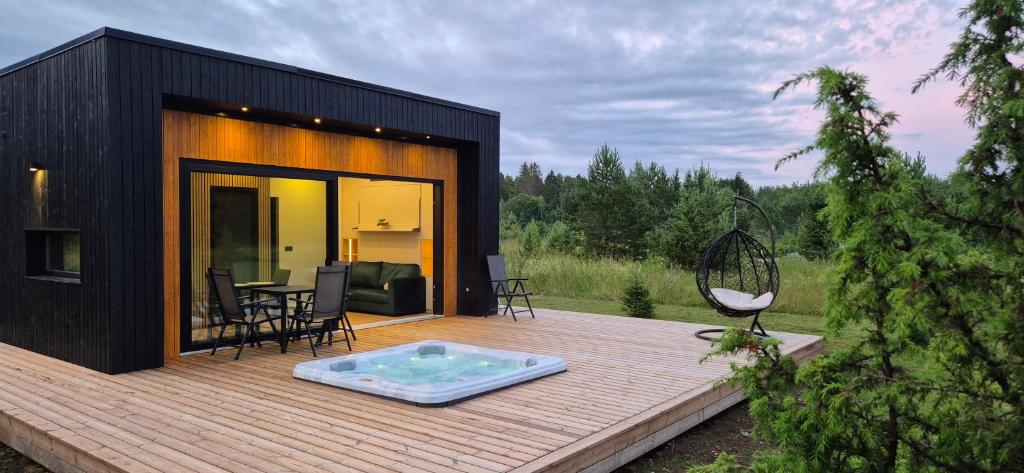 Una casa negra con terraza de madera y piscina. en Paus, en Kernu