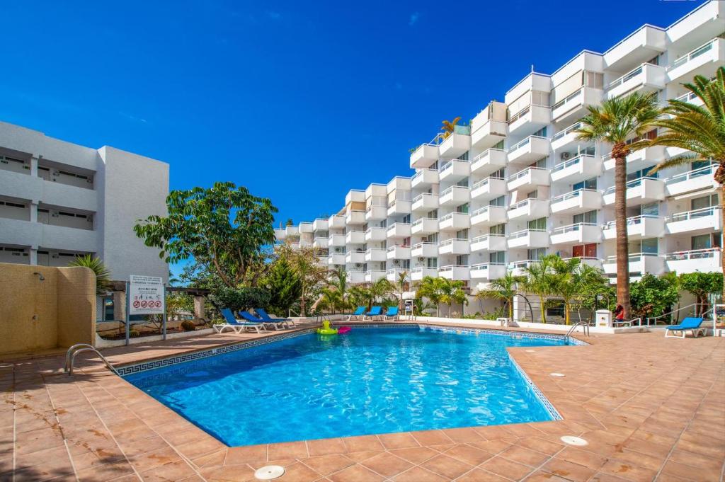 Costa de AdejeにあるEliss apartmentの大きなアパートメントの建物の前にスイミングプールがあります。
