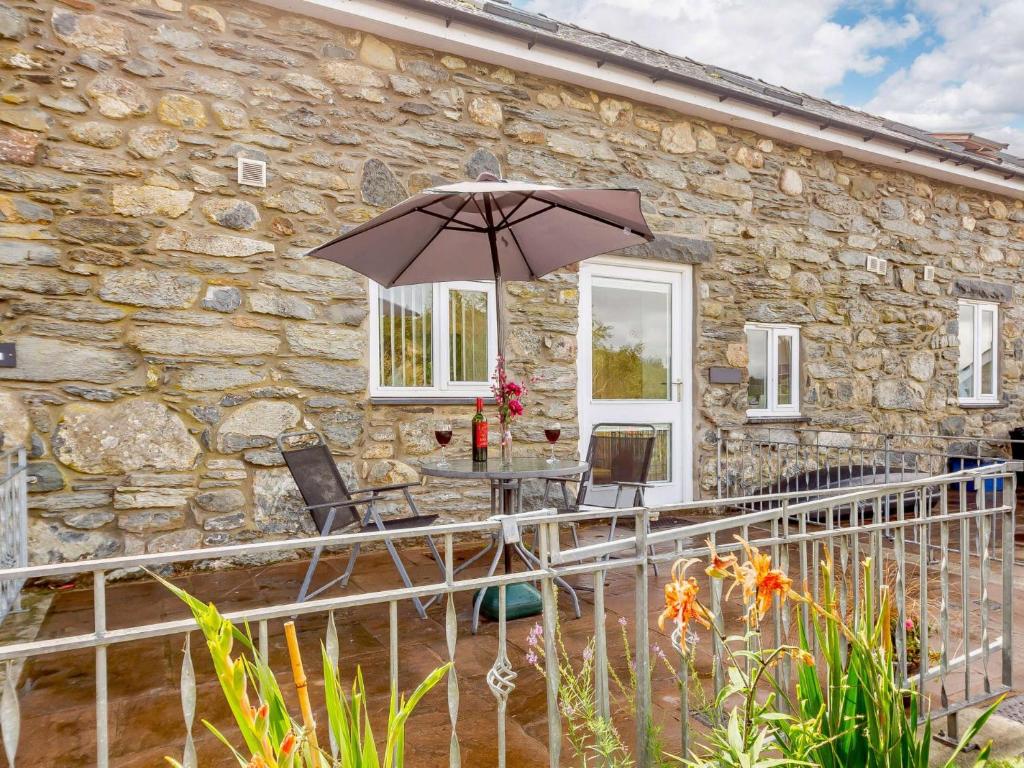 Cabaña de piedra con mesa y sombrilla en 1 Bed in Bala 89369, en Llandderfel