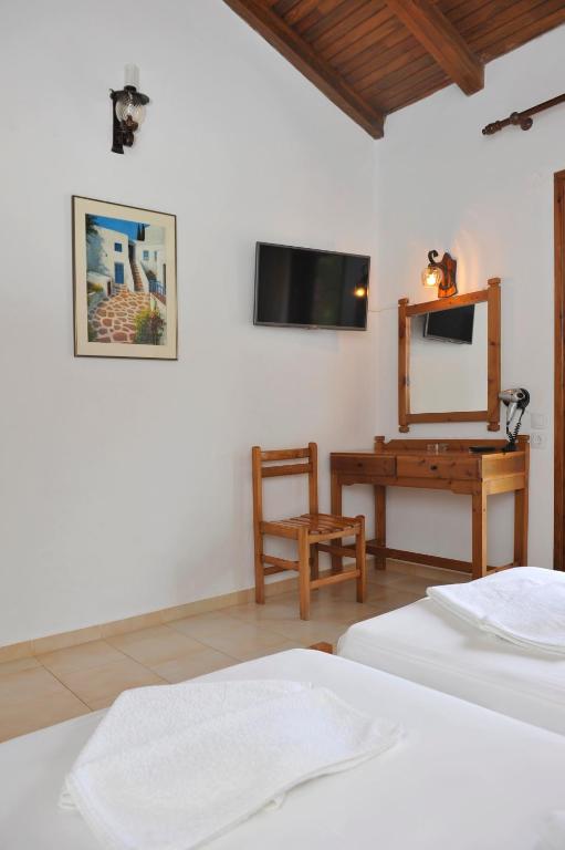 a bedroom with two beds and a desk with a mirror at Villa Anna Maria in Agia Paraskevi