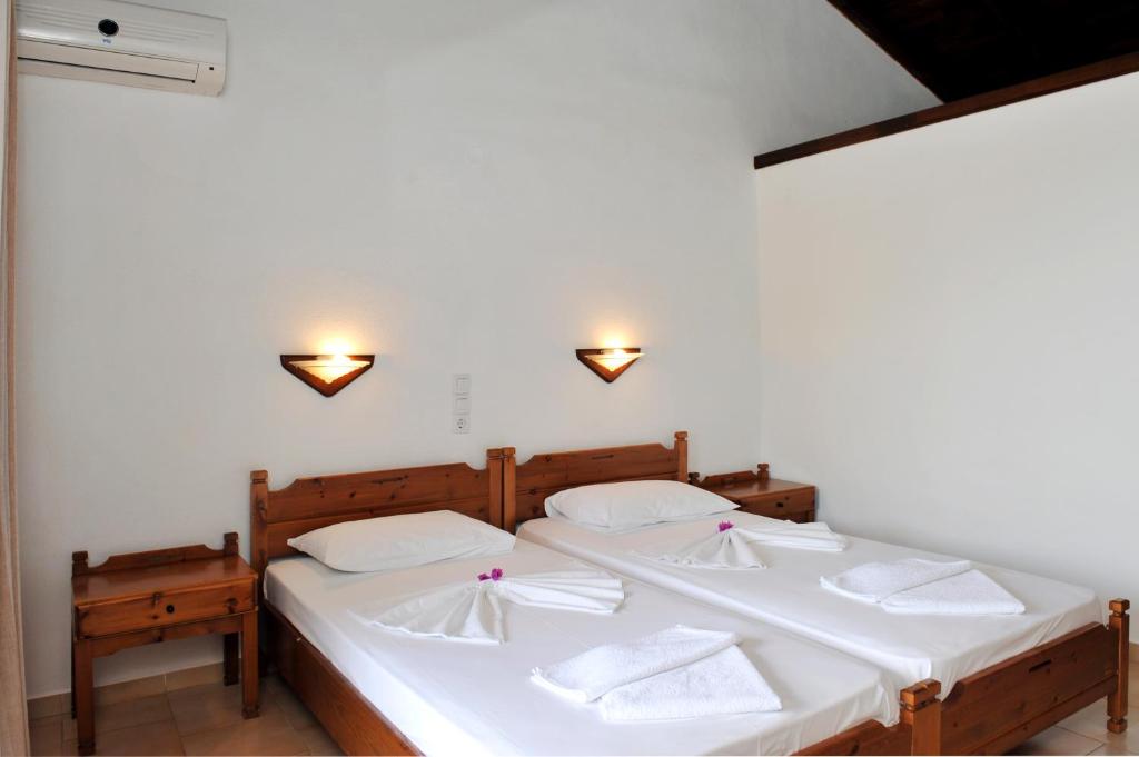 a bedroom with two beds with white sheets and towels at Villa Anna Maria in Agia Paraskevi