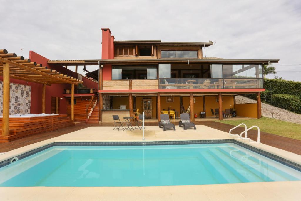 una casa con piscina delante de una casa en Mirantes Paraibuna - Casa Vermelha, en Paraibuna