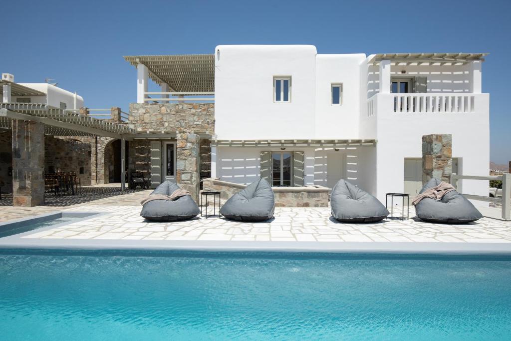 a villa with a swimming pool in front of a house at Ventus Studios in Ano Mera