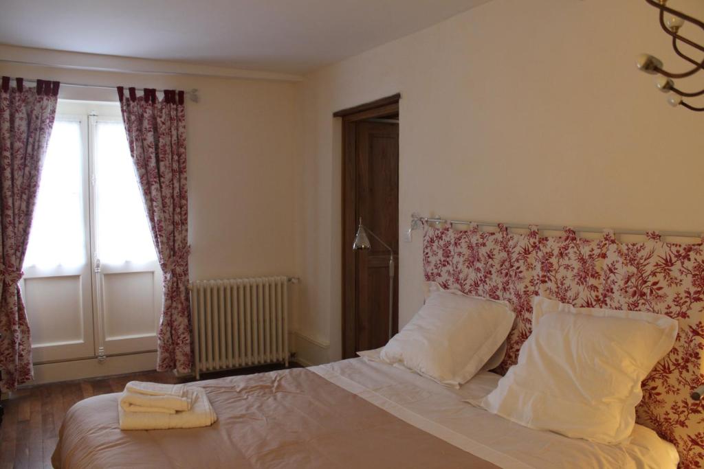 1 dormitorio con 1 cama con 2 almohadas y ventana en Cellier de l'abbaye - L'Ermitage, en Vézelay