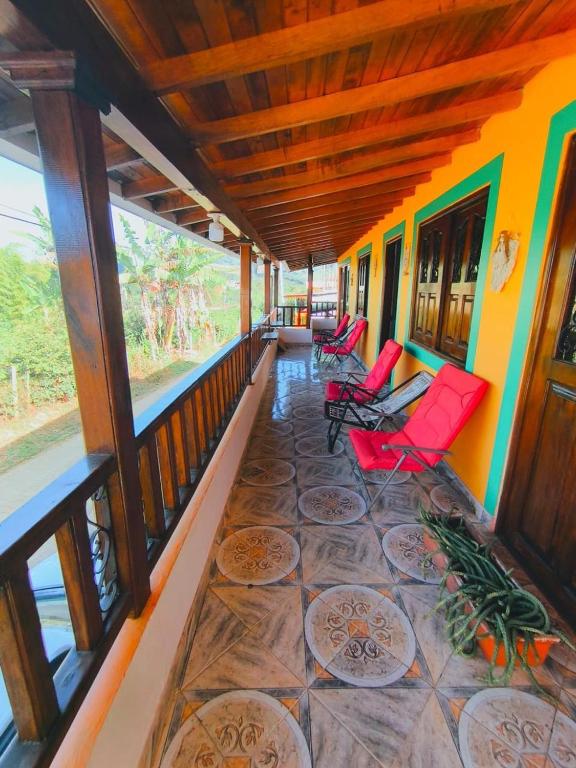a porch of a house with red chairs and windows at Finca La Carolina in Jericó