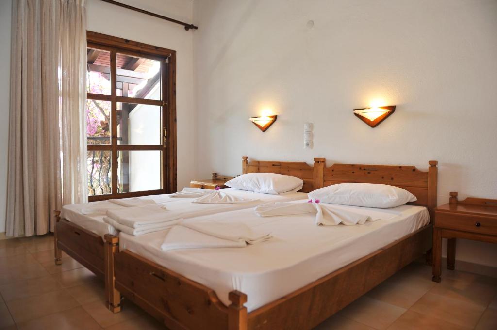 two twin beds in a room with a window at Villa Anna Maria in Agia Paraskevi