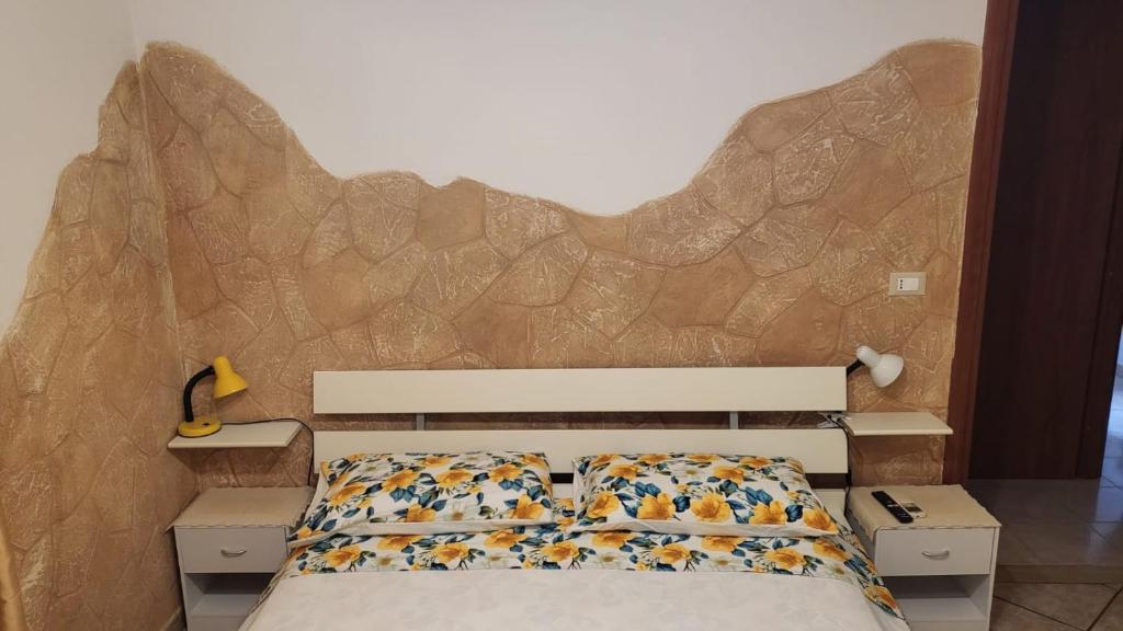 a bedroom with a bed with a stone wall at la finestra sul cortile 2 in Santa Procula Maggiore