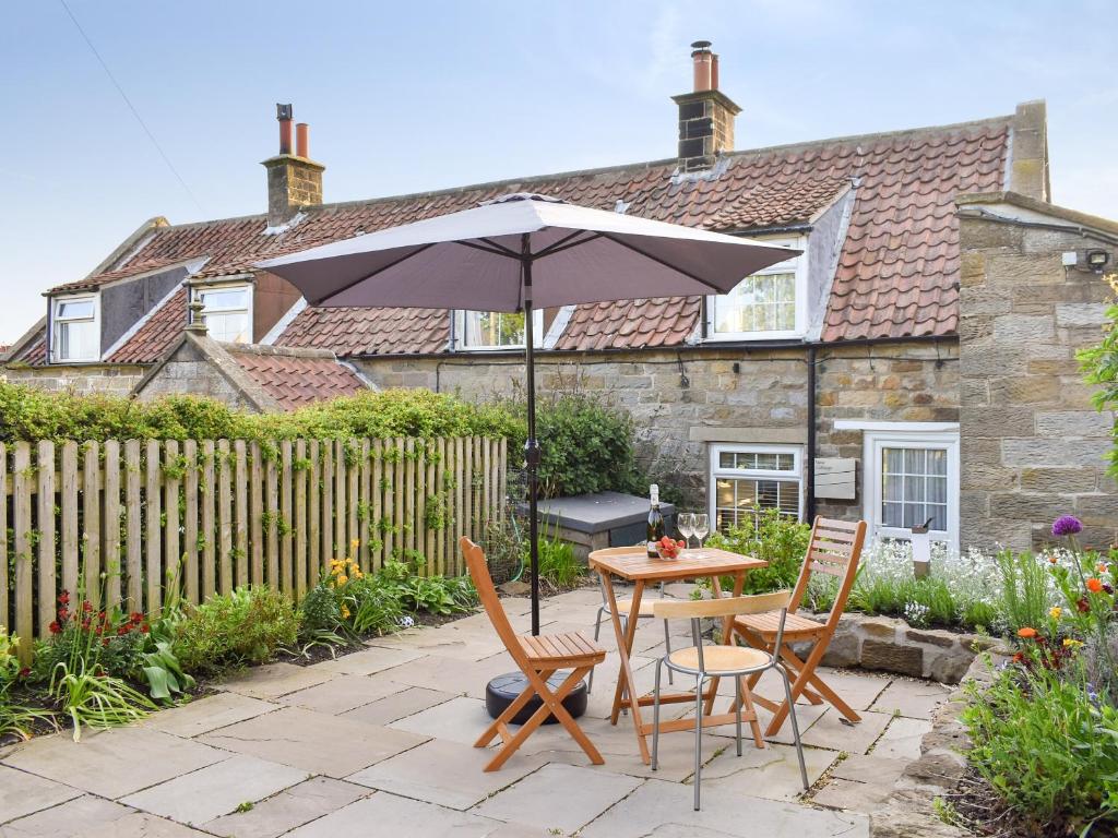 a patio with a table and chairs and an umbrella at New Cottage in Egton