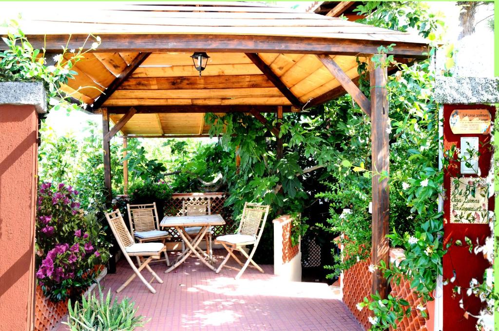 a patio with a table and chairs under a wooden pergola at B&B Casa Derosas in Golfo Aranci