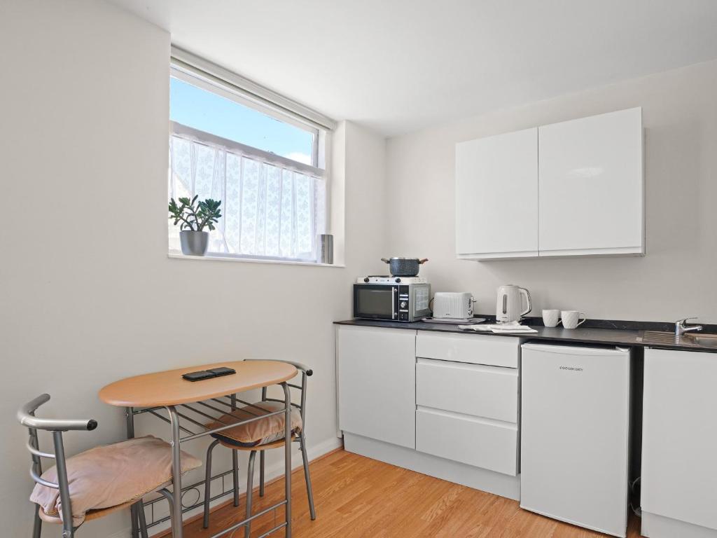 a kitchen with white cabinets and a table and chairs at Gable End Coastal Retreat in Great Yarmouth