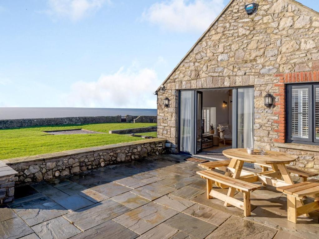 a stone cottage with a wooden table and a picnic bench at 2 Bed in Ogmore-by-Sea 86495 in Southerndown