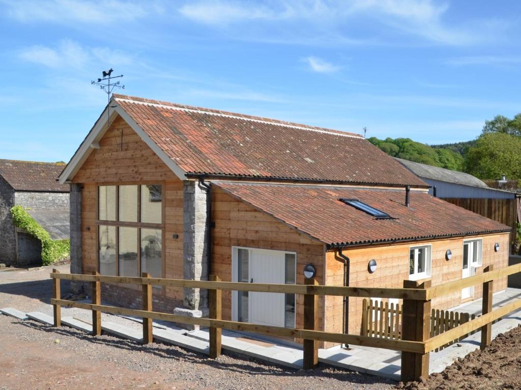 a barn conversion with a wooden fence in front of it at 3 Bed in Cheddar 58129 in Burrington