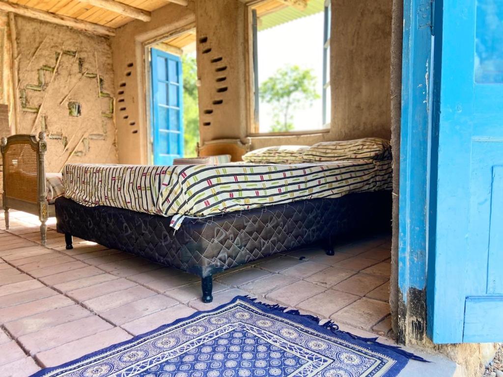 a bed in a room with a window and a rug at Finca Zen, naturaleza y agroecologia in San Rafael