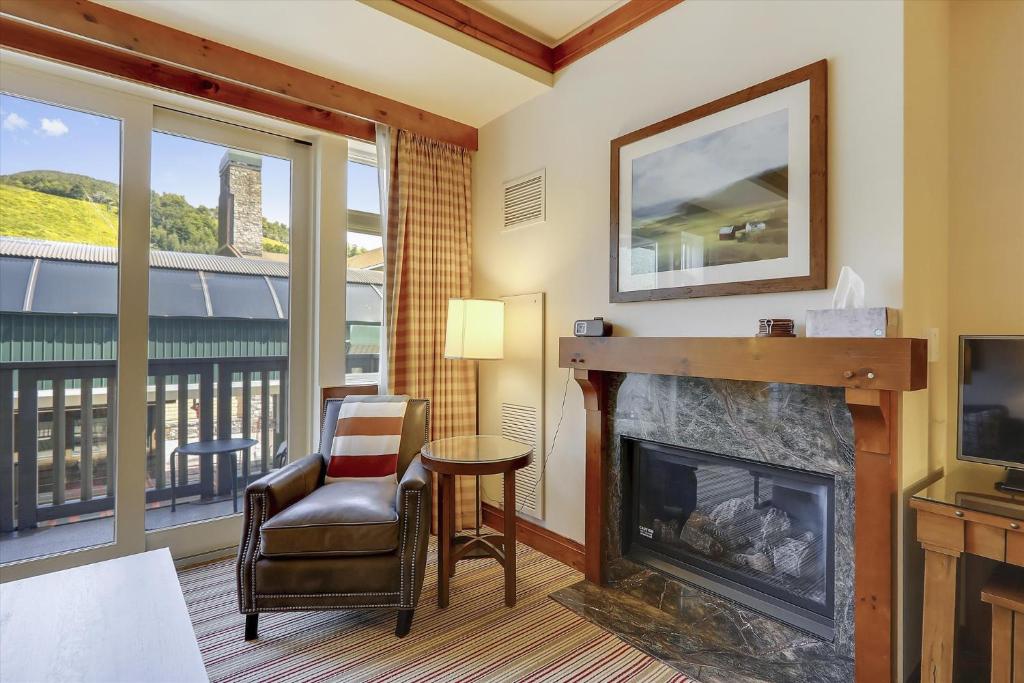 un salon avec une cheminée, une chaise et une télévision dans l'établissement Studio 373 at The Lodge at Spruce Peak, à Stowe Mountain
