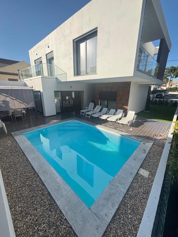 a villa with a swimming pool in front of a house at Aroeira Beach Home in Almada