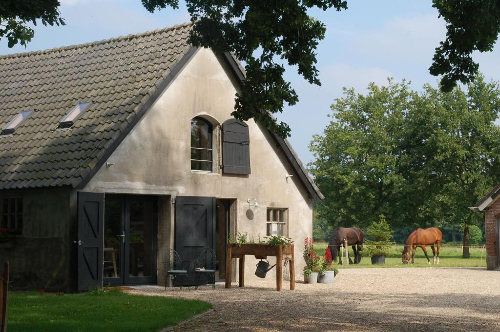 a white building with two horses in a field at Klein Dubbelland in Doorn
