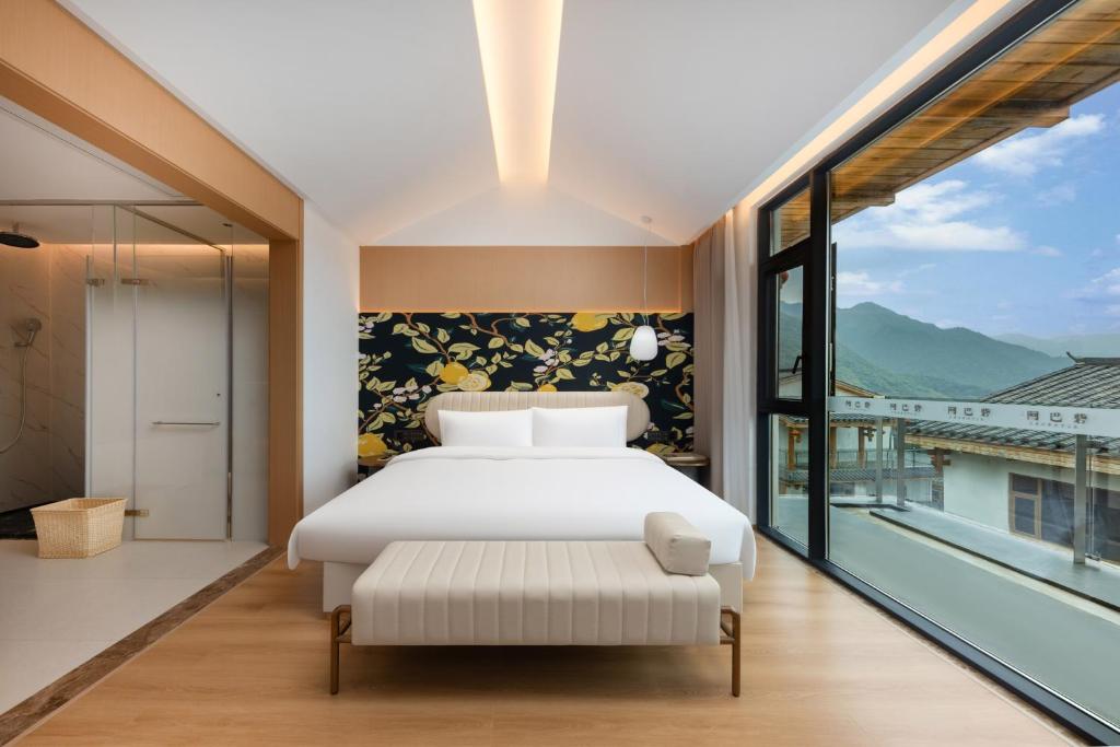 a bedroom with a white bed and a large window at Zhangjiajie Valley Secret Resort in Zhangjiajie