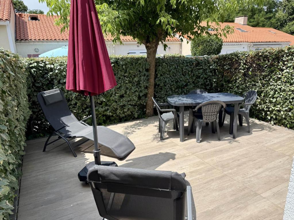 un patio avec une table, des chaises et un parasol dans l'établissement AGREABLE APPARTEMENT REFAIT A NEUF DANS UNE RESIDENCE DE VACANCES - FR-1-92-946, à Les Sables-dʼOlonne