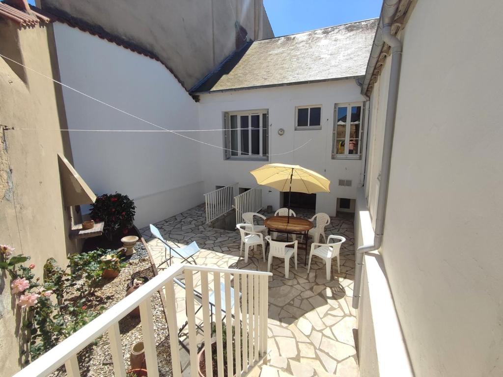 un patio avec une table, des chaises et un parasol dans l'établissement Maison 3 ch, cour privée et Wi-Fi, proche plage et commerces - FR-1-92-949, à Les Sables-dʼOlonne