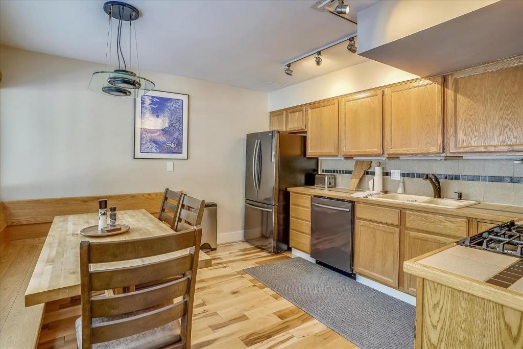 a kitchen with wooden cabinets and a table and a refrigerator at Tollhouse 10B in Stowe Fork