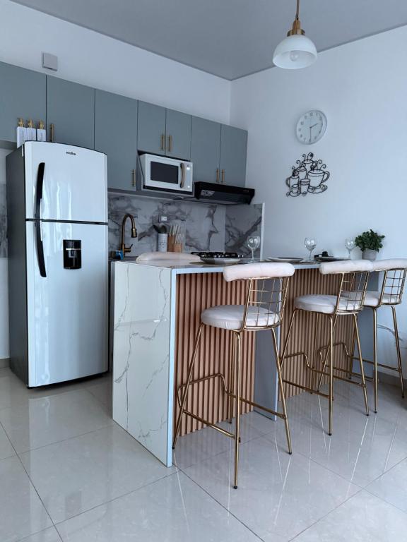 a kitchen with a white refrigerator and some bar stools at Elegante casa a minutos de Centro comercial in San Miguel