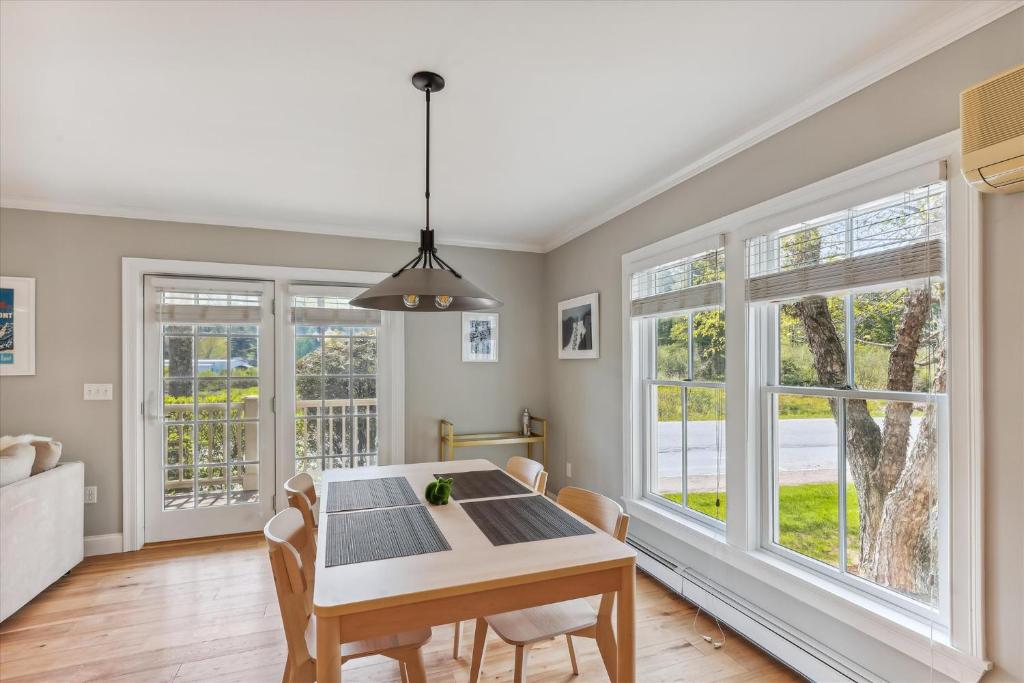 a dining room with a table and chairs and windows at Village Sunrise in Stowe