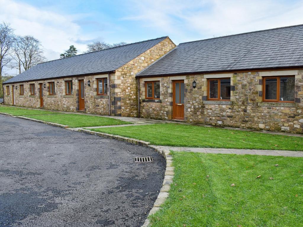 a stone house with a grass yard next to a street at Six Dorchester Drive - Uk32627 in Inglewhite