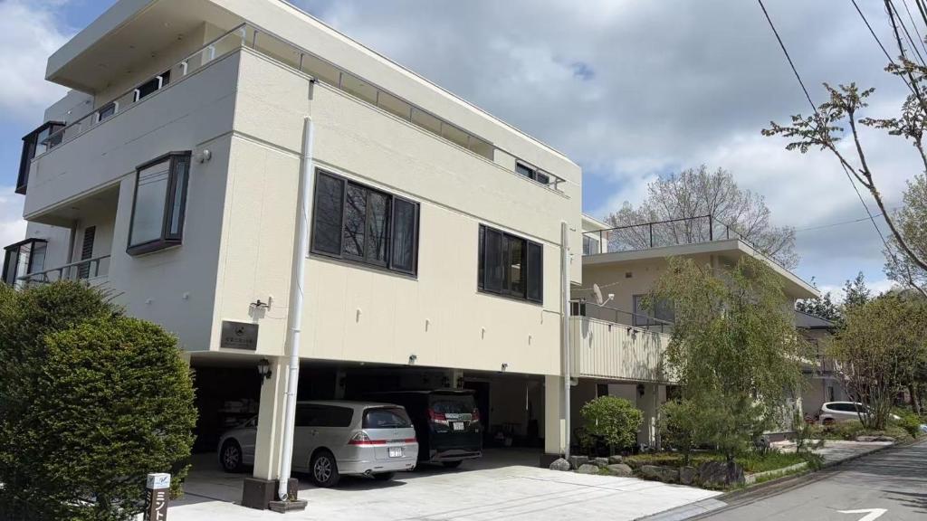 a white building with cars parked in a parking lot at 紅富士苑 in Yamanakako