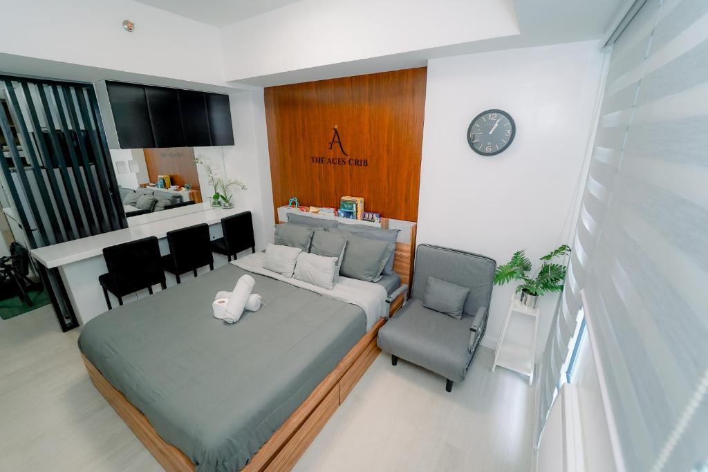 a bedroom with a bed and two chairs and a clock at The Aces Crib at Azure North Pampanga in San Fernando