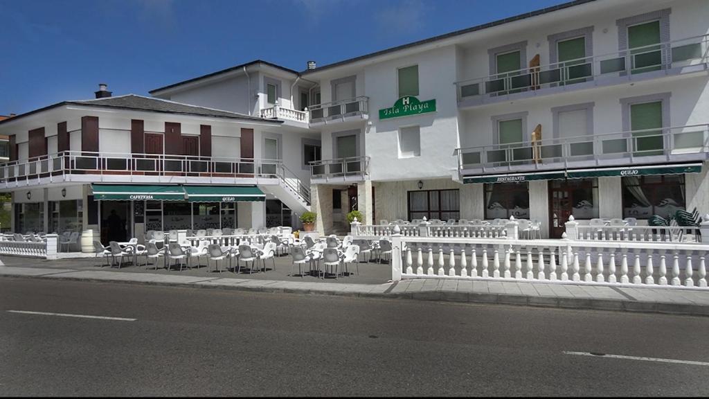 a building with tables and chairs in front of a street at Hostal Isla Playa in Isla