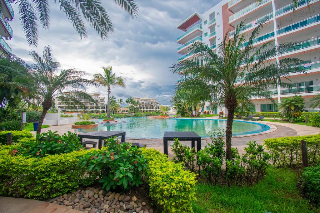 a pool at the resort with palm trees and buildings at Condominio en la marina Pacifika in Los Cerritos
