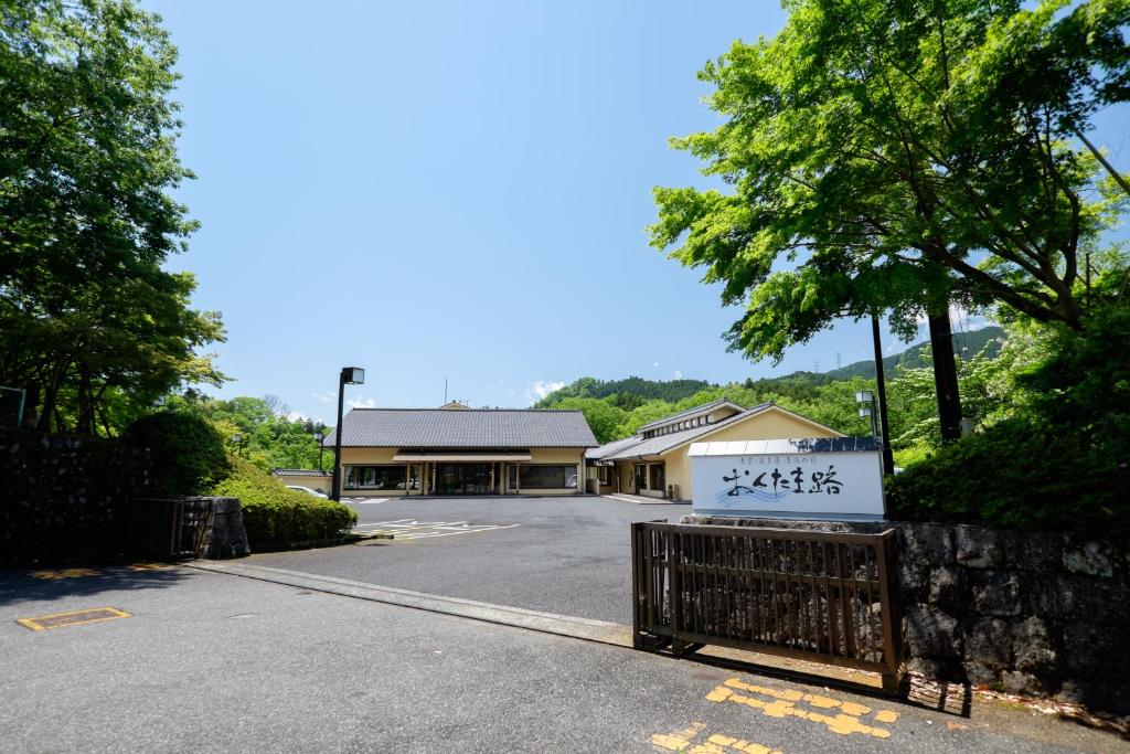 ein Gebäude mit einem Schild vor einem Parkplatz in der Unterkunft Okutamaji in Ome
