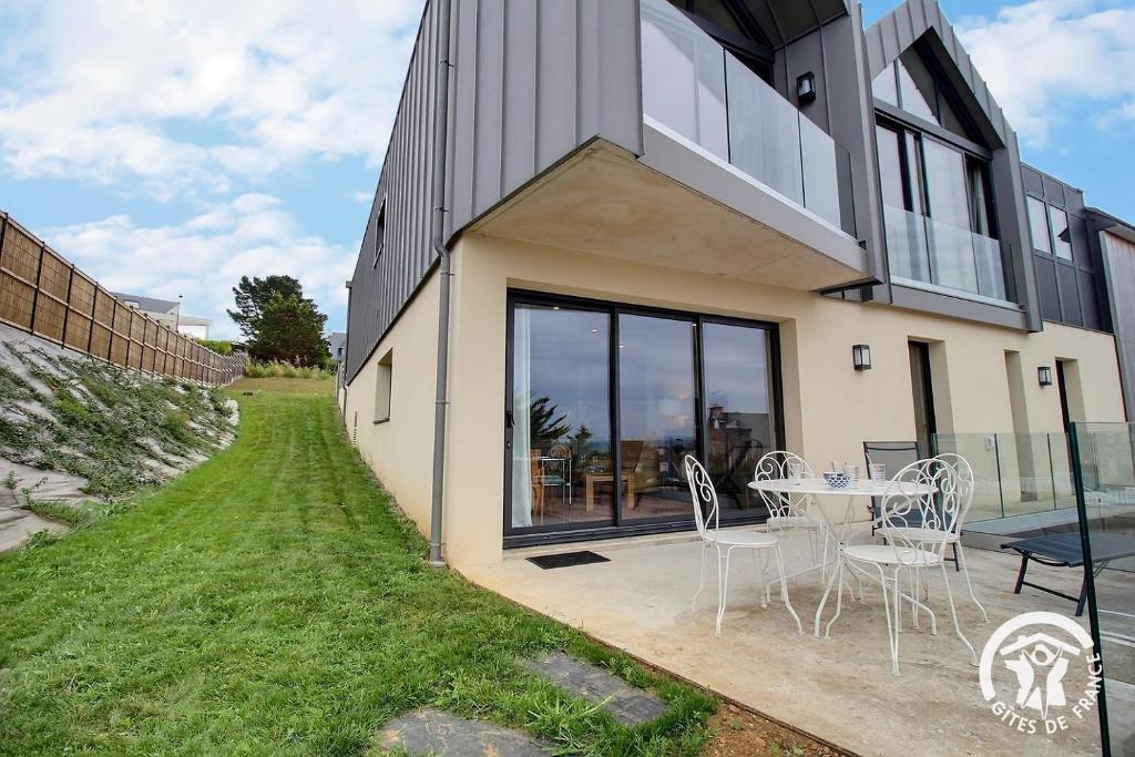 a house with a patio with a table and chairs at Les belles vues d'erquy in Erquy