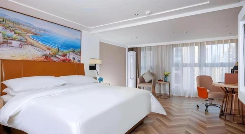 ein Schlafzimmer mit einem großen weißen Bett und einem Schreibtisch in der Unterkunft Vienna Hotel Chengdu Exhibition Center In Time City in Chengdu