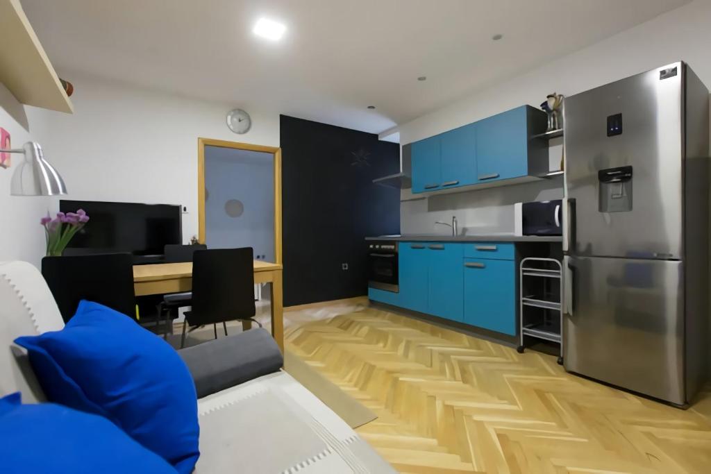 a kitchen and living room with blue cabinets and a table at Cosy Big Apartment in Zagreb