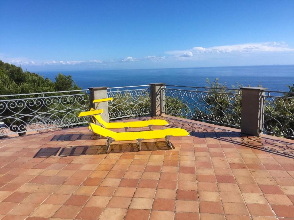 un banc jaune assis sur un balcon donnant sur l'océan dans l'établissement B&B Le Palme, à Ameglia