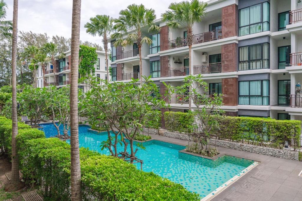 an apartment building with a swimming pool and palm trees at C219 1BR Island Hideaway 500m to Rawai Beach in Rawai Beach