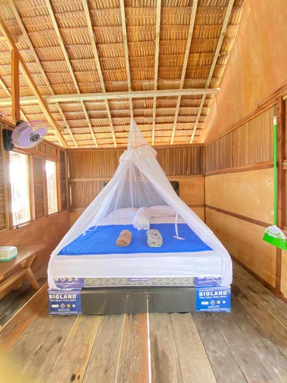 a bed in a room with a mosquito net at Famwall Homestay Raja Ampat in Keruo