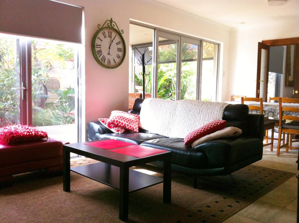 a living room with a couch and a clock on the wall at Mt Lawley Garden Apartment in Perth