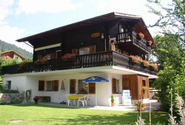 ein großes Haus mit einem Balkon und einem Tisch in der Unterkunft Ferienwohnung Jasmin in Fiesch