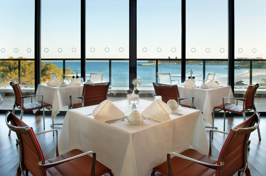 a meeting room with white tables and chairs and windows at Martinhal Sagres Beach Family Resort Hotel in Sagres