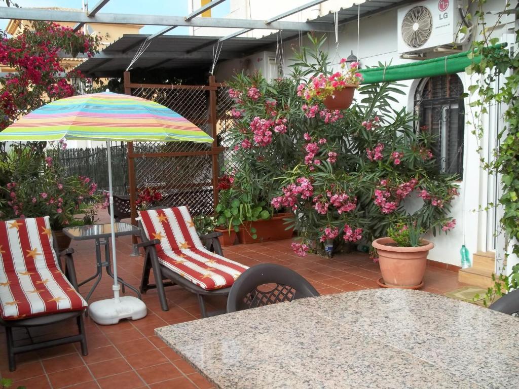 un patio con sillas, sombrilla y flores en Madamme Curie Apartment, en Torrevieja